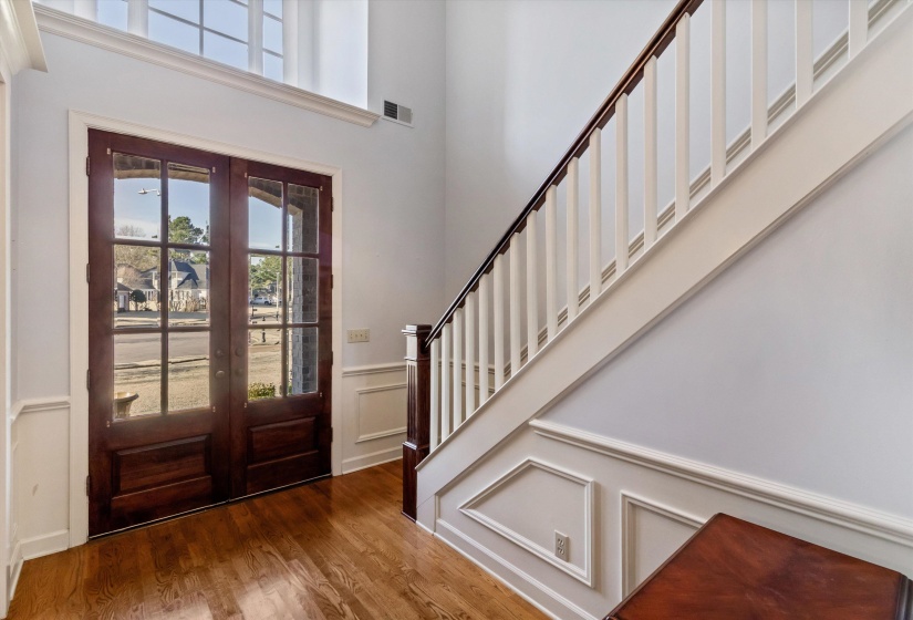 Entrance foyer featuring french doors, wood finished floors, a decorative wall, a wainscoted wall, and stairs