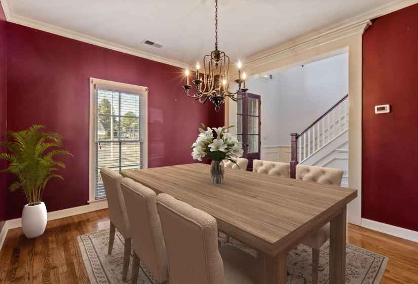 Dining room with a chandelier, wood finished floors, crown molding, and stairs
