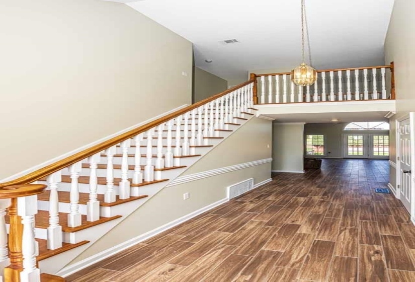 Staircase with wood finish floors, french doors, hanging lights, and a high ceiling