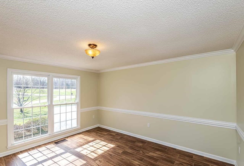 Empty room with dark wood-style flooring, ornamental molding, and a textured ceiling