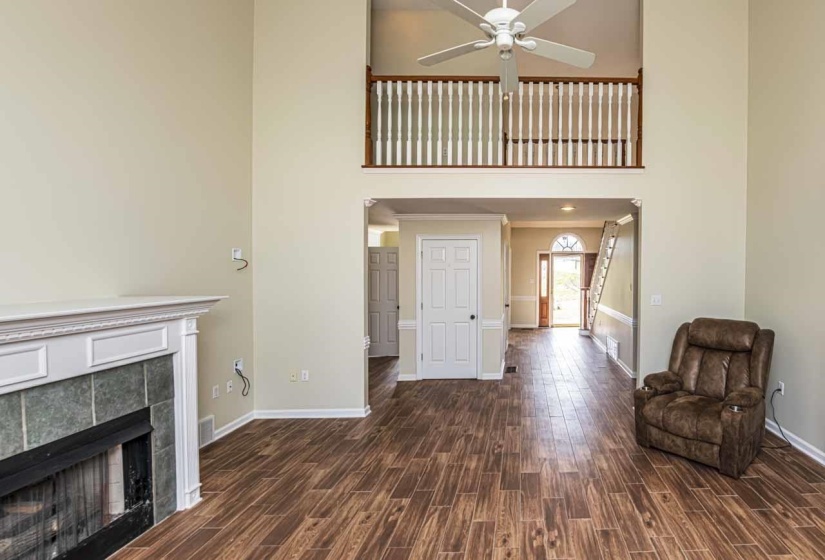 Unfurnished living room featuring wood tiled floors, a high ceiling, a fireplace, and a ceiling fan