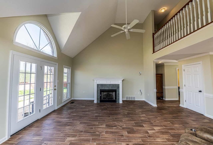 Unfurnished living room featuring wood tiled floors, a tile fireplace, vaulted ceiling, and ceiling fan