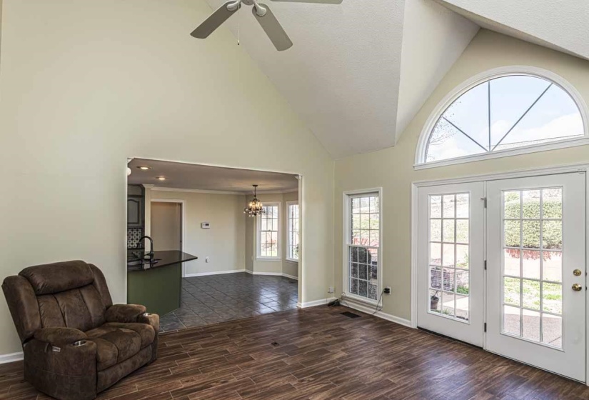 Sitting room featuring wood finish floors, a high textured ceiling, a ceiling fan, and a chandelier