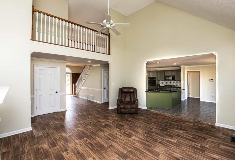 Unfurnished living room with wood tiled floors, a ceiling fan, and lofted ceiling
