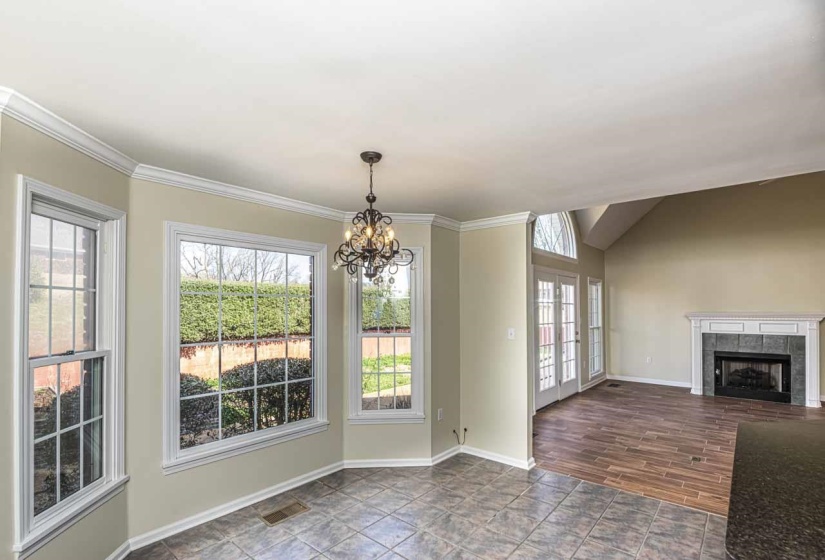 Unfurnished dining area with a tiled fireplace, a chandelier, plenty of natural light, and wood finish floors