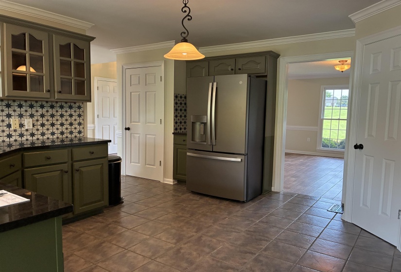 Kitchen featuring olive-toned cabinetry, a stainless steel French door refrigerator, black countertops, and a patterned tile backsplash