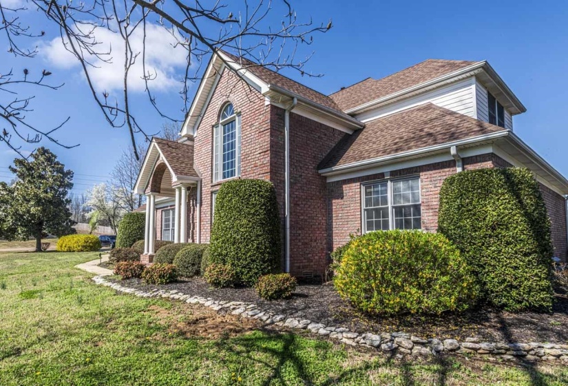 View of side of home featuring a yard, brick siding, and a shingled roof