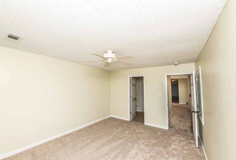 Unfurnished bedroom featuring light colored carpet, a ceiling fan, and a textured ceiling