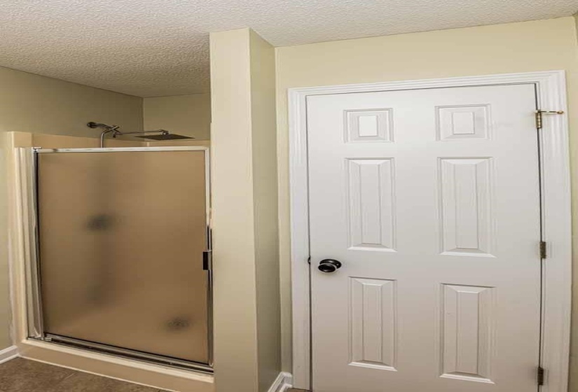 Bathroom featuring a textured ceiling and a shower stall