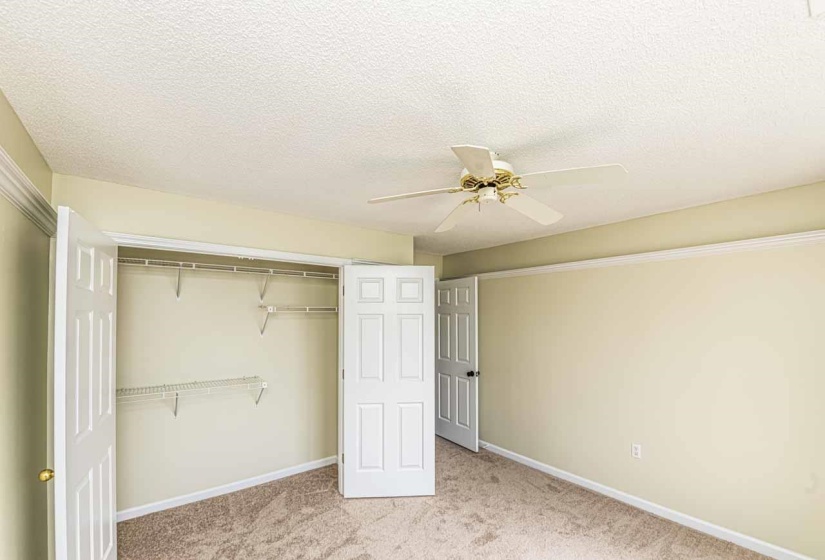 Unfurnished bedroom featuring light carpet, a closet, a textured ceiling, and a ceiling fan