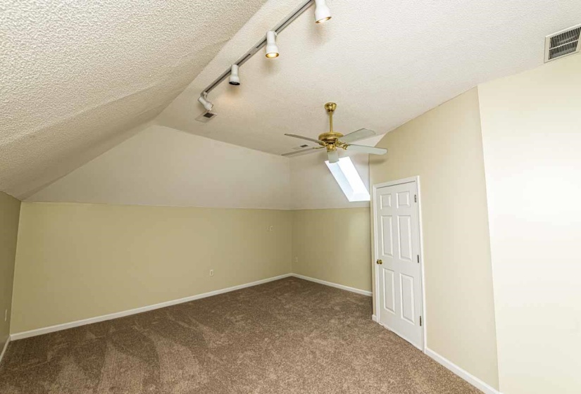 Bonus room featuring dark colored carpet and ceiling fan