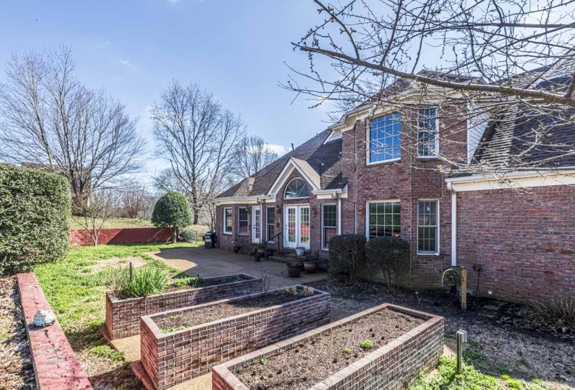 View of front of house with a garden, brick siding, french doors, and a shingled roof