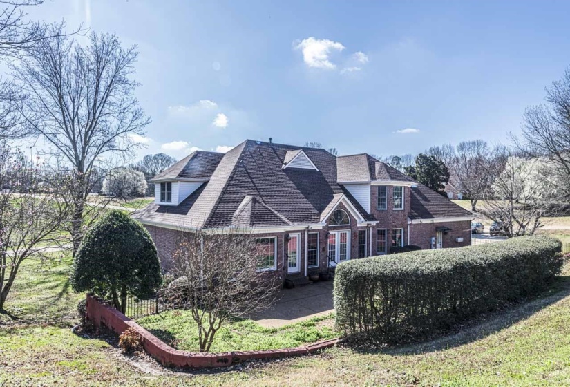 View of front of property featuring brick siding and roof with shingles