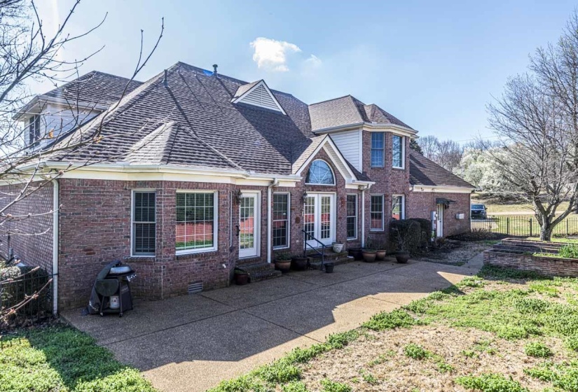 View of front facade with brick siding, entry steps, a patio area, and a shingled roof