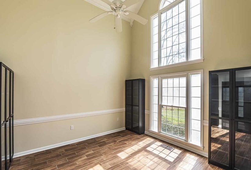Unfurnished room with wood finish floors, a ceiling fan, and a high ceiling