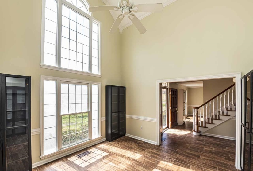 Entrance foyer with wood tiled floors, a ceiling fan, ornamental molding, and a high ceiling