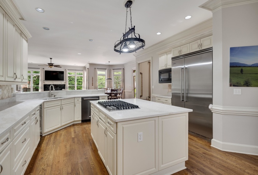 Gourmet kitchen featuring a central island with gas cooktop, recessed and pendant lighting, stainless steel appliances, white cabinetry, and wood-finish flooring