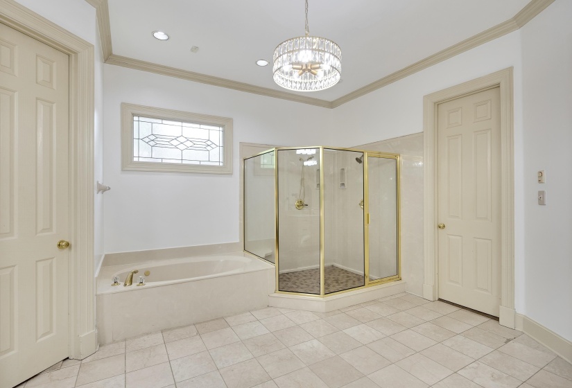 Spacious bathroom featuring a built-in tub, separate glass-enclosed shower, tiled flooring, and a decorative frosted window
