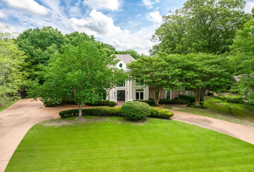 Traditional-style residence with a circular drive, mature trees, and a verdant lawn