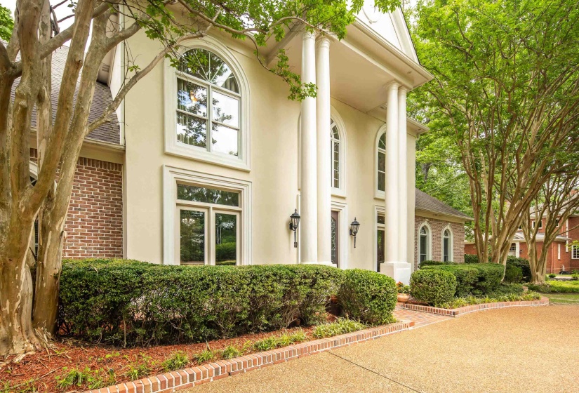 Stucco and brick facade featuring a portico with four columns and arched windows