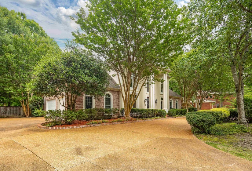 Stately Colonial-style residence featuring a brick and stucco facade, decorative columns, and arched windows