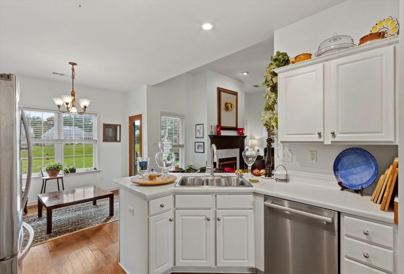 Kitchen featuring white cabinetry, stainless steel dishwasher, and a corner sink with a goose-neck faucet