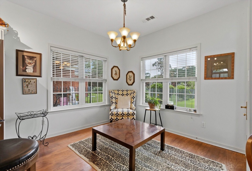 Room featuring wood-finish flooring, white walls, and a multi-light chandelier