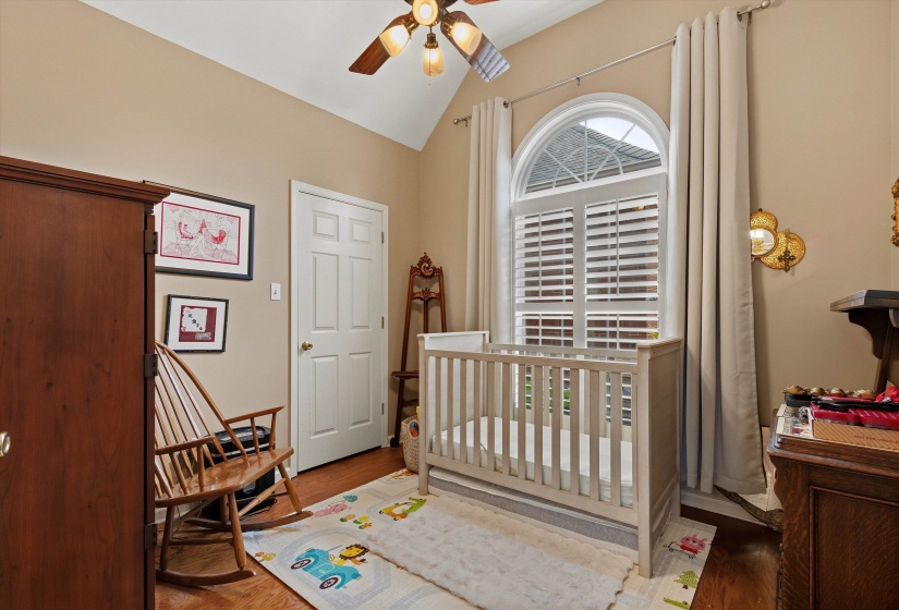 Room with vaulted ceiling, wood-finish flooring, arched window with plantation shutters, and a ceiling fan with integrated lighting