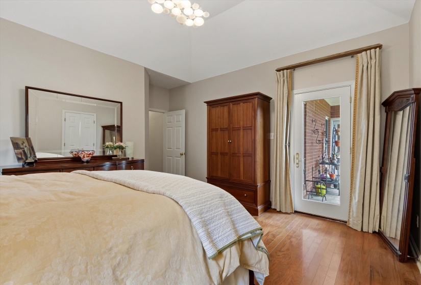 Vaulted ceiling with an updated light fixture, wood-finish flooring, and a glass-paneled exterior door