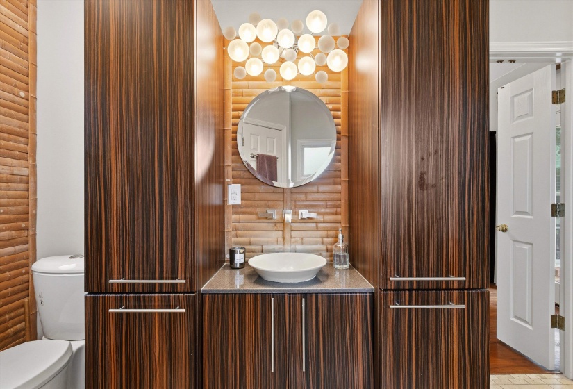 Vanity featuring dark wood-finish cabinetry, a vessel sink, and a circular mirror