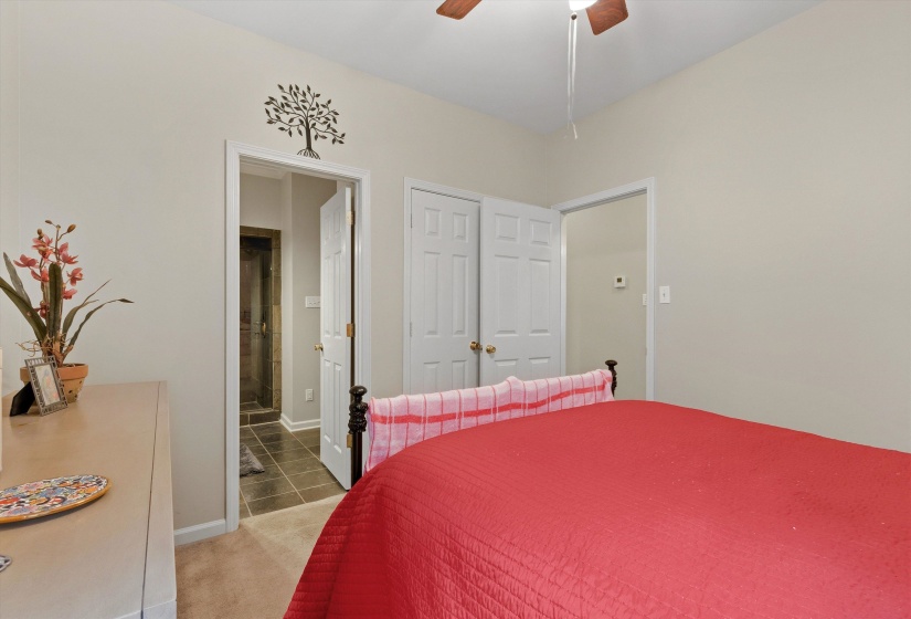 Bedroom featuring neutral wall color, carpet flooring, a ceiling fan, and a doorway leading to a tiled area