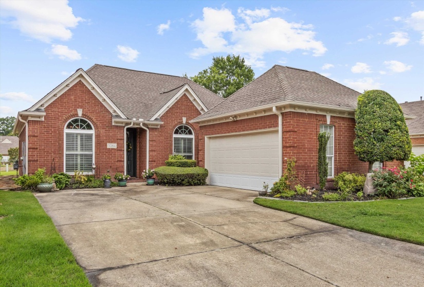Red brick exterior with white trim, arched windows, and an attached garage
