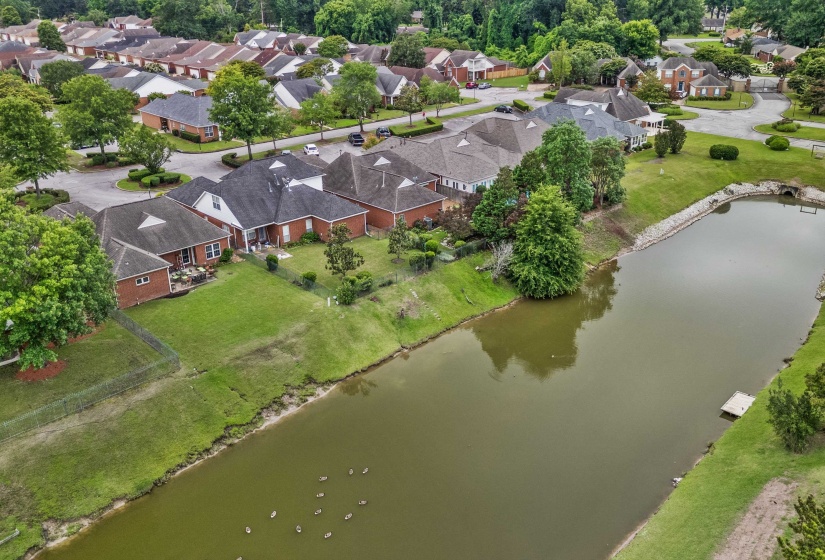 Waterfront property featuring a private dock, mature trees, and a brick exterior