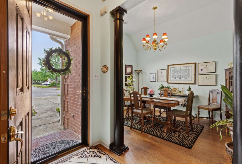 Expansive dining area featuring wood-finish flooring, a vaulted ceiling, and a brass chandelier with amber-toned shades