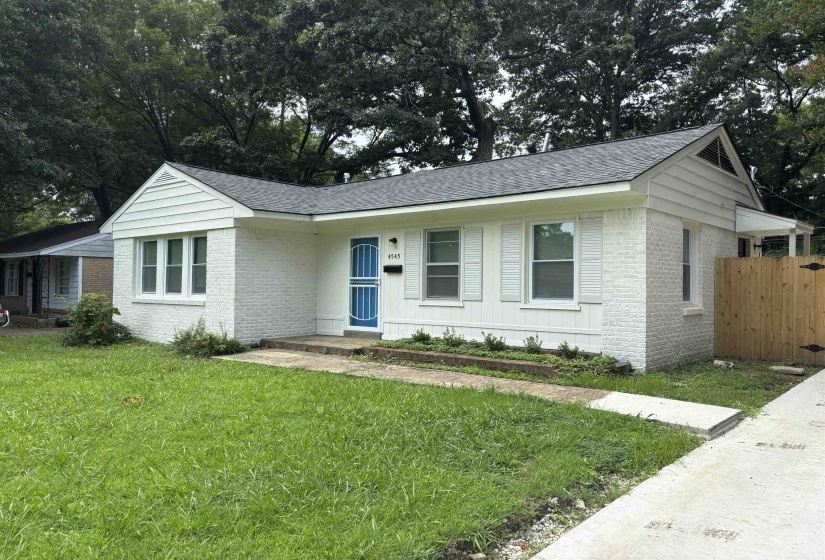 White brick exterior featuring a newly installed dark shingle roof and a vibrant blue security screen door