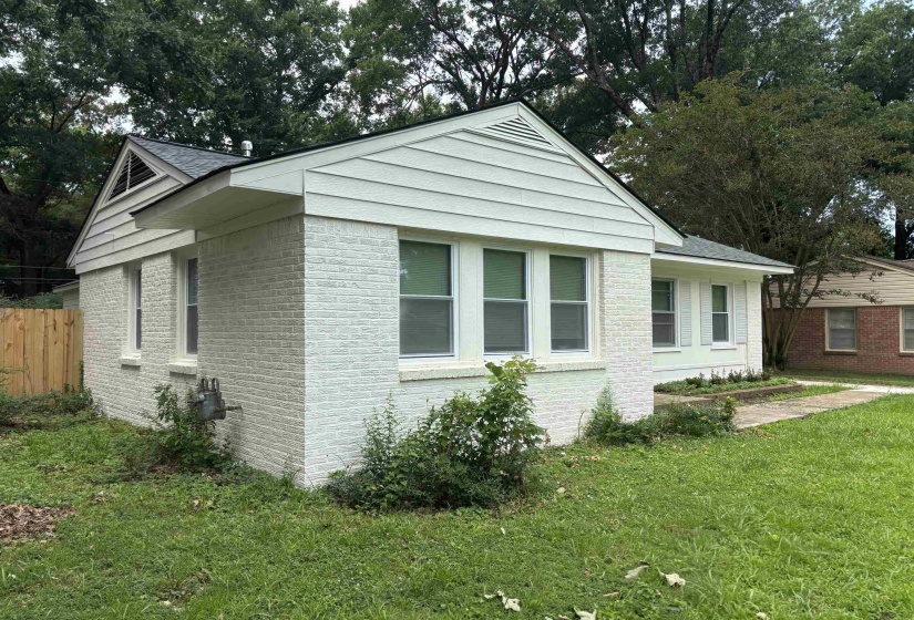 White painted brick exterior with white siding and a dark shingle roof