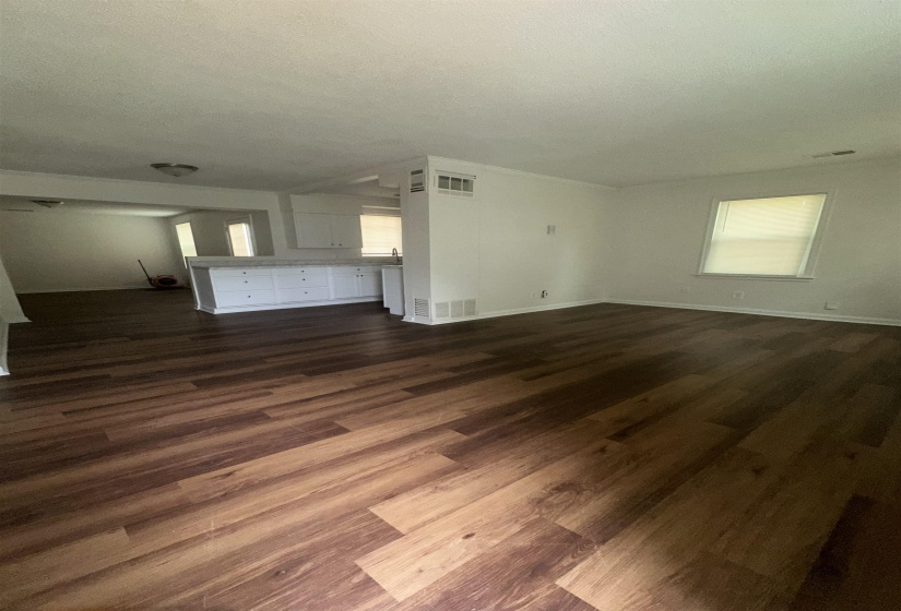 Open-concept living space featuring wood-finish flooring, white walls, and crown molding