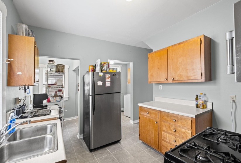 Kitchen featuring light wood cabinetry, white countertops, a double basin stainless steel sink, and a black gas range