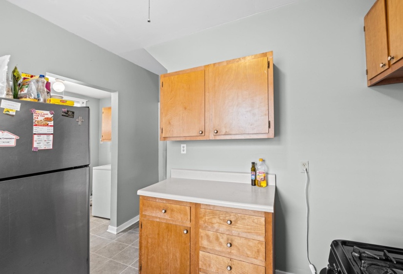 Kitchen featuring natural wood cabinetry, light countertops, and tile flooring