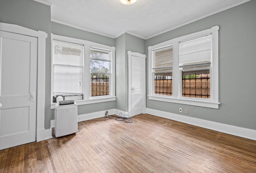 Room featuring wood-finish flooring, light gray walls, and multiple windows with white blinds