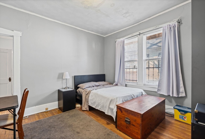 Light-filled room featuring wood-finish flooring, white trim, and a double window with blinds