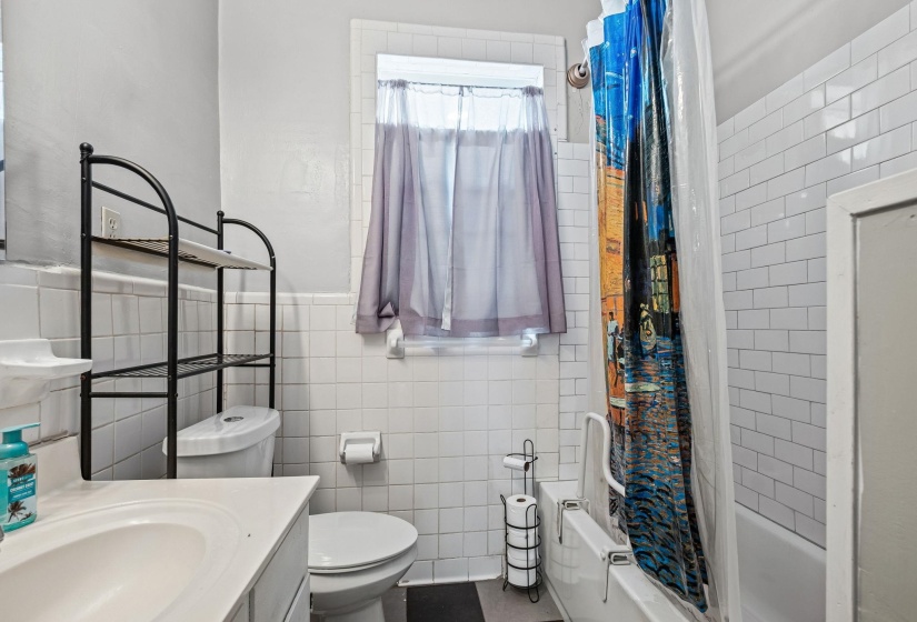 Bathroom featuring a white ceramic tile wainscoting and a white subway tile shower surround