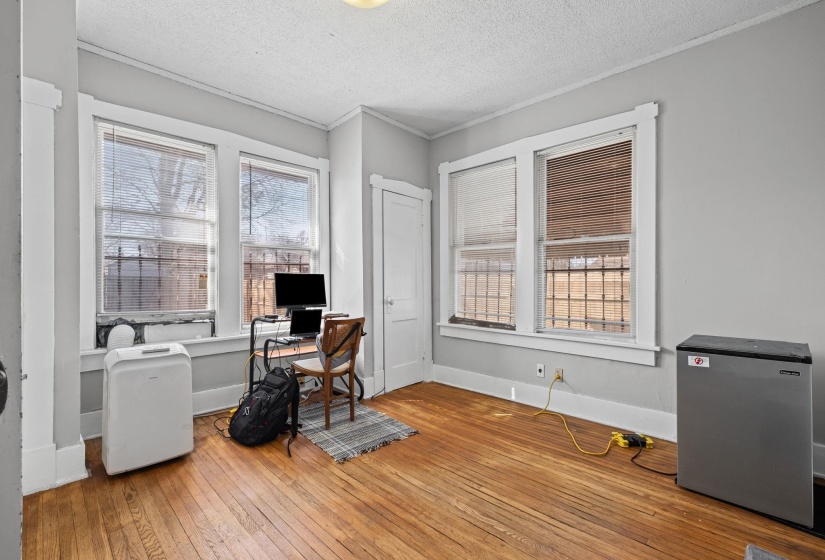 Hardwood flooring throughout this room featuring multiple windows, a white door, and light gray walls