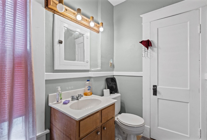 Bathroom featuring a wood-finish vanity with an integrated sink, a medicine cabinet, and a five-bulb fixture