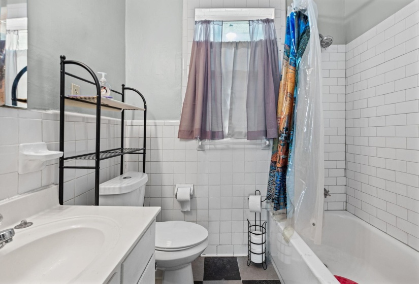 Bathroom featuring a white subway tile shower surround, a built-in bathtub, and a window with natural light