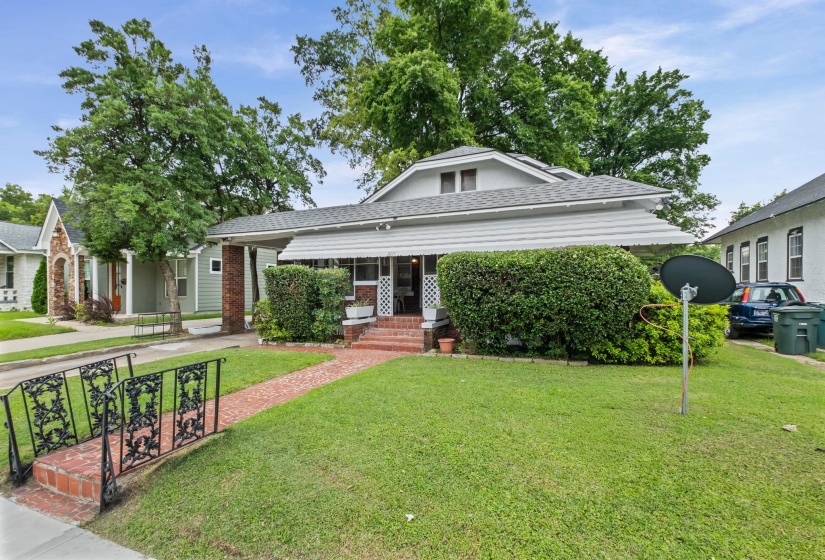 Front exterior featuring a covered porch, brick steps, and a red brick pathway