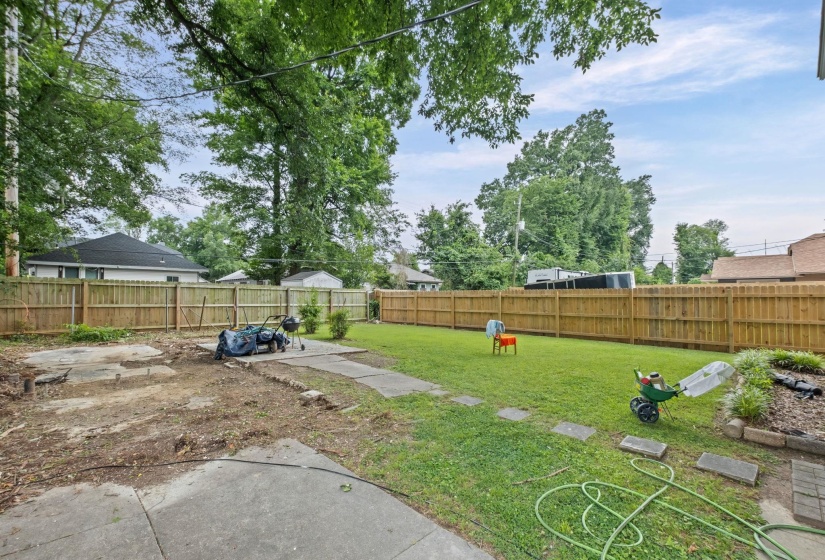 Expansive backyard featuring a combination of concrete patio areas and a central grassy lawn