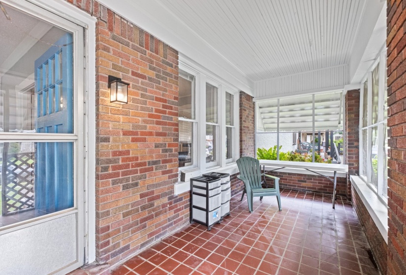 Enclosed front porch featuring a multi-toned brick wall and white plank ceiling