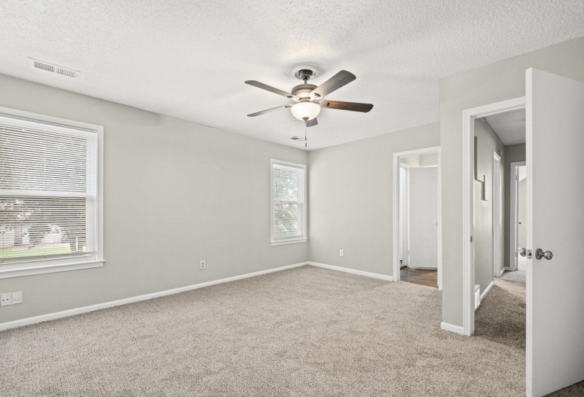 Carpeted interior space featuring light gray wall paint, white trim, and two windows with blinds