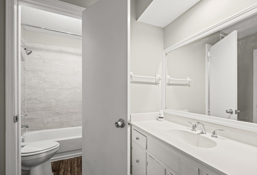Full bathroom featuring an integrated sink vanity with chrome fixtures and a large framed mirror